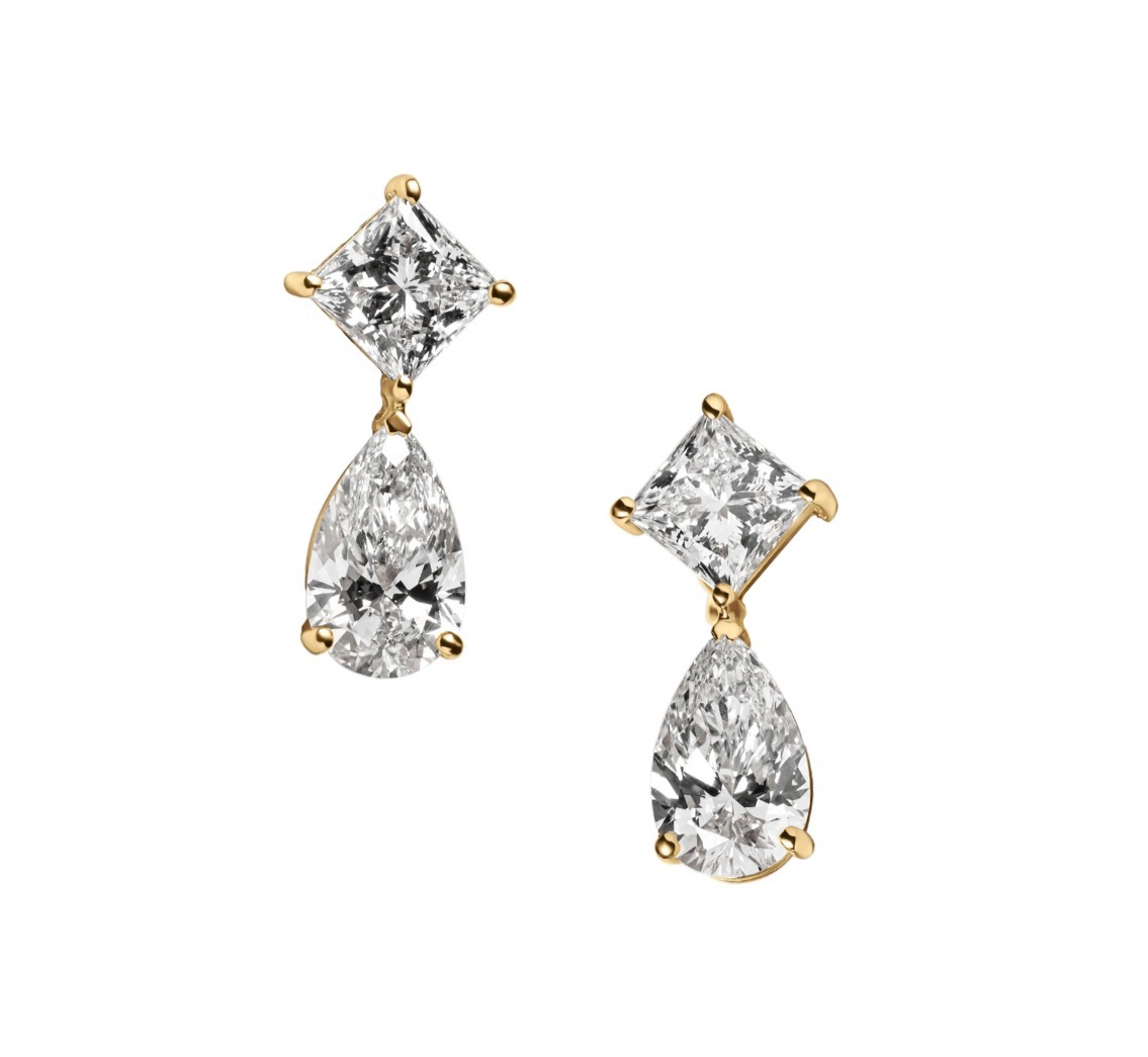 A pair of lab-grown diamond drop earrings featuring a princess-cut diamond at the top and a pear-shaped diamond below, set in a sleek gold prong setting against a white background.
