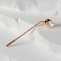 Rose gold lapel pin featuring an oval-cut lab-grown diamond, elegantly displayed on a textured white surface with layered details.
